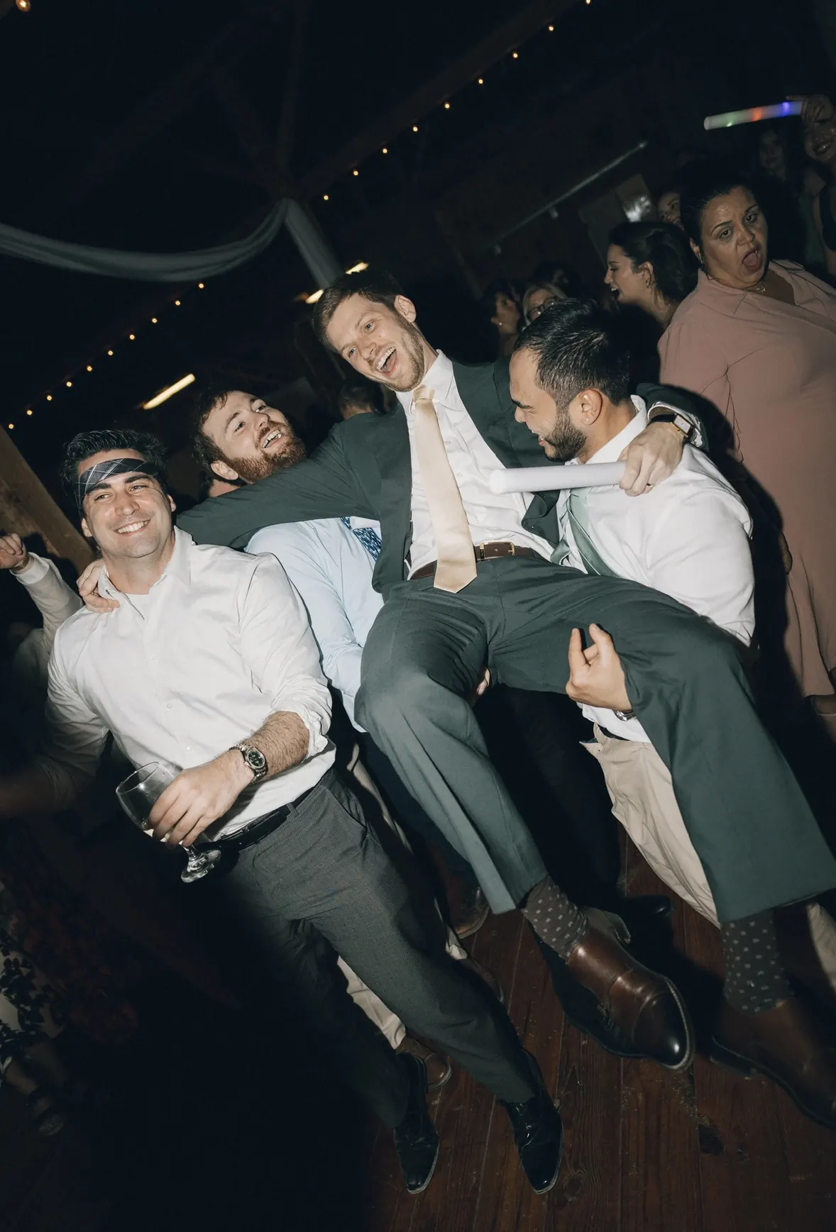 Groomsmen lifting the groom on the dance floor