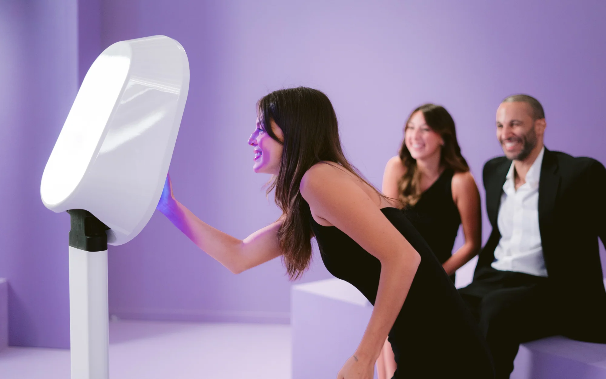 Guest using a digital photo booth at a party while friends laugh